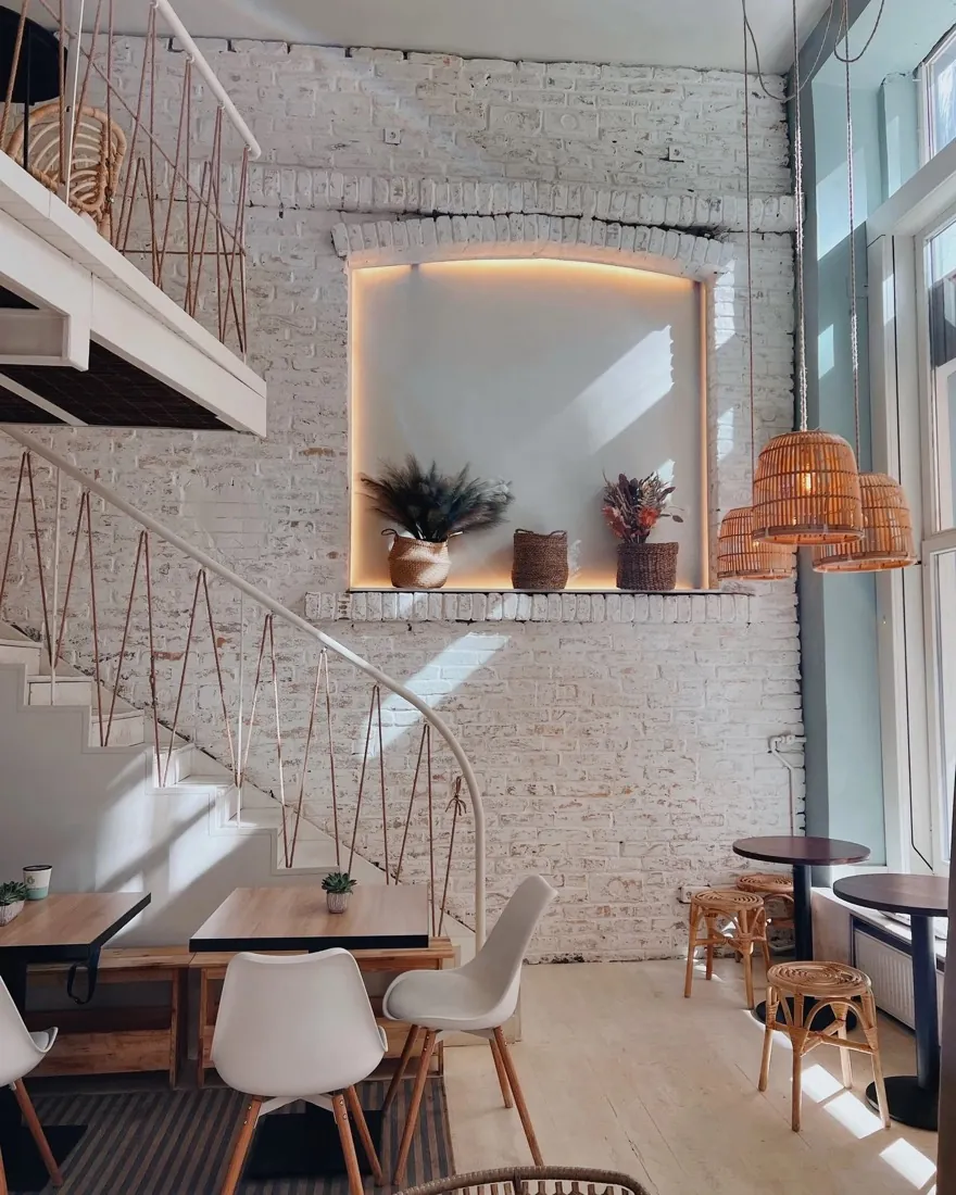 Inside a Cookie Beacon brunch spot — white brick, a spiral staircase and warm light