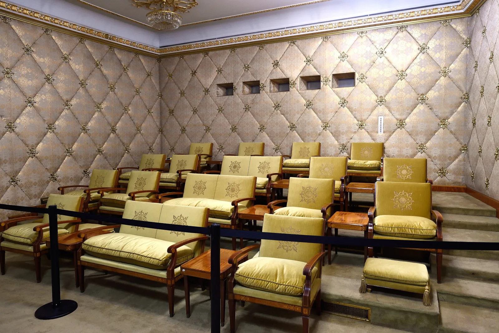 Sala de cinema privată din Palatul Primăverii: fotolii galbene așezate în trepte și pereți tapițați în romburi