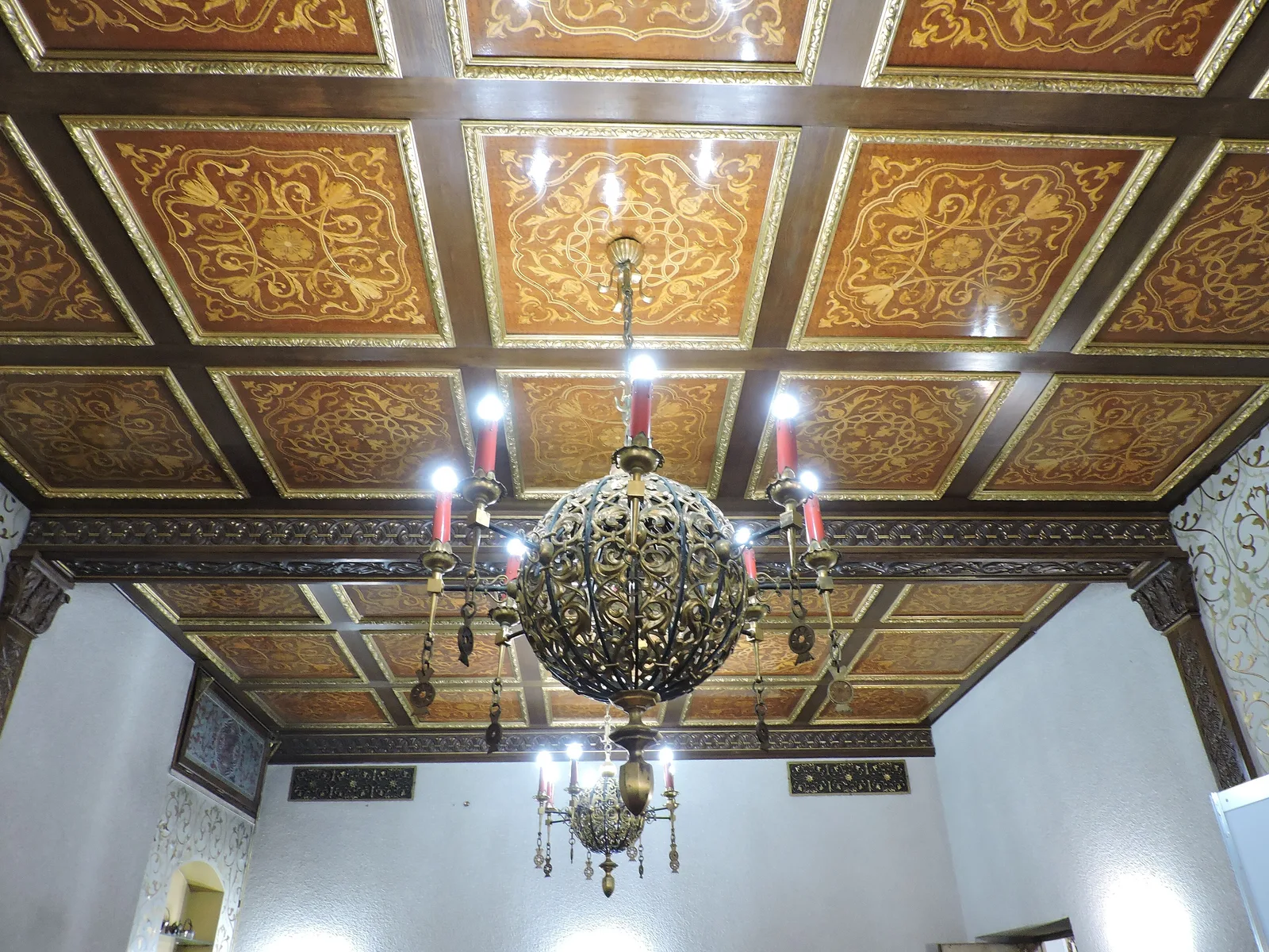 Tavan casetat din lemn cu ornamente aurii și candelabru, într-o cameră a Palatului Primăverii din București