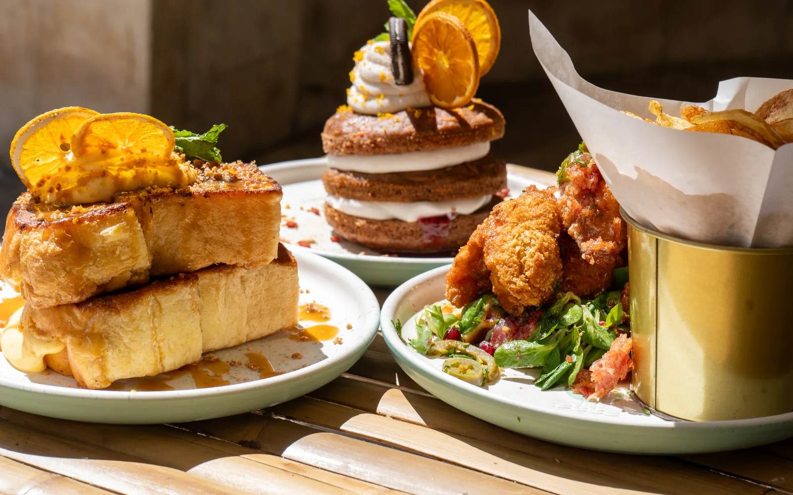 A shared brunch table at Cookie Beacon: crème brûlée French toast, a carrot-cake pancake stack and a chicken and waffles stack
