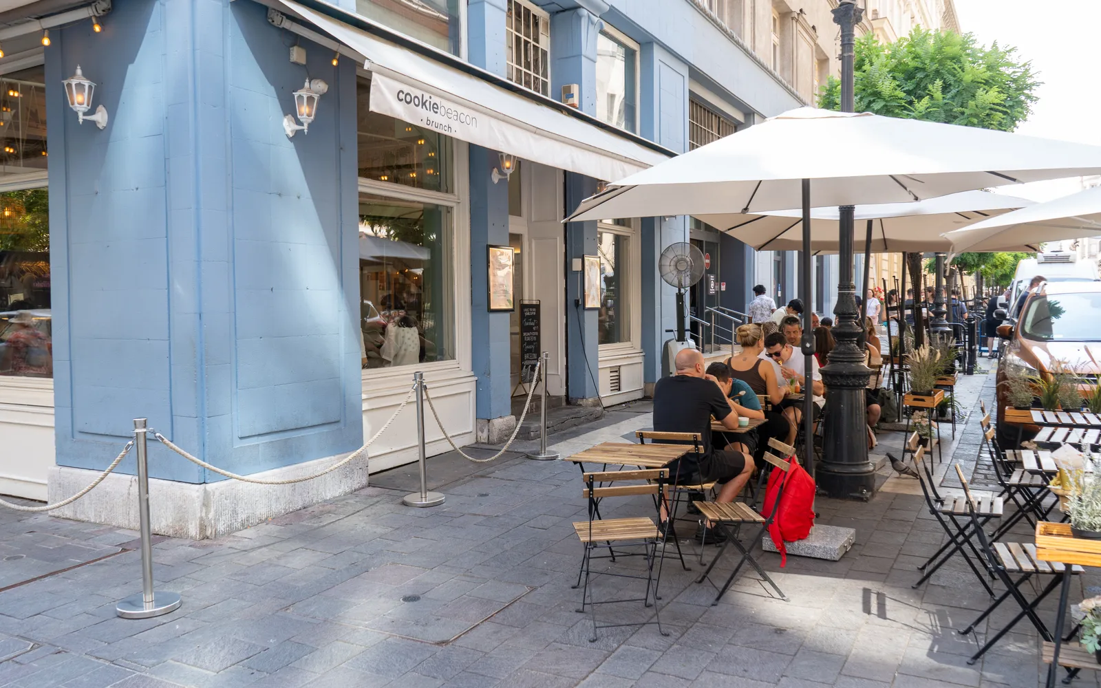 Pavement tables under white parasols on the terrace outside Cookie Beacon on Hercegprímás utca in Budapest