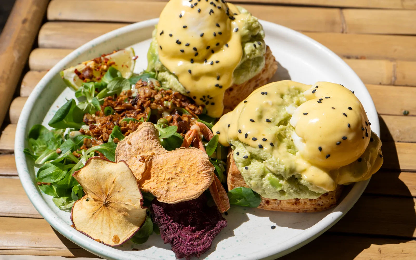 Eggs Benedict on cheddar scones — poached eggs under hollandaise with avocado-feta smash and mixed salad — at Cookie Beacon