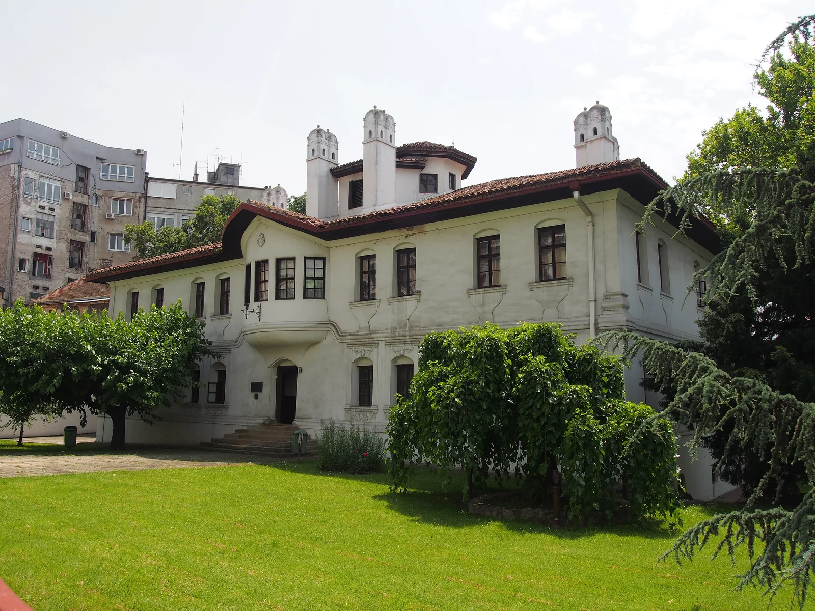 Princess Ljubica's Residence in Belgrade: a white two-storey 1830 house with a red tiled roof, a row of chimneys and a green lawn in front