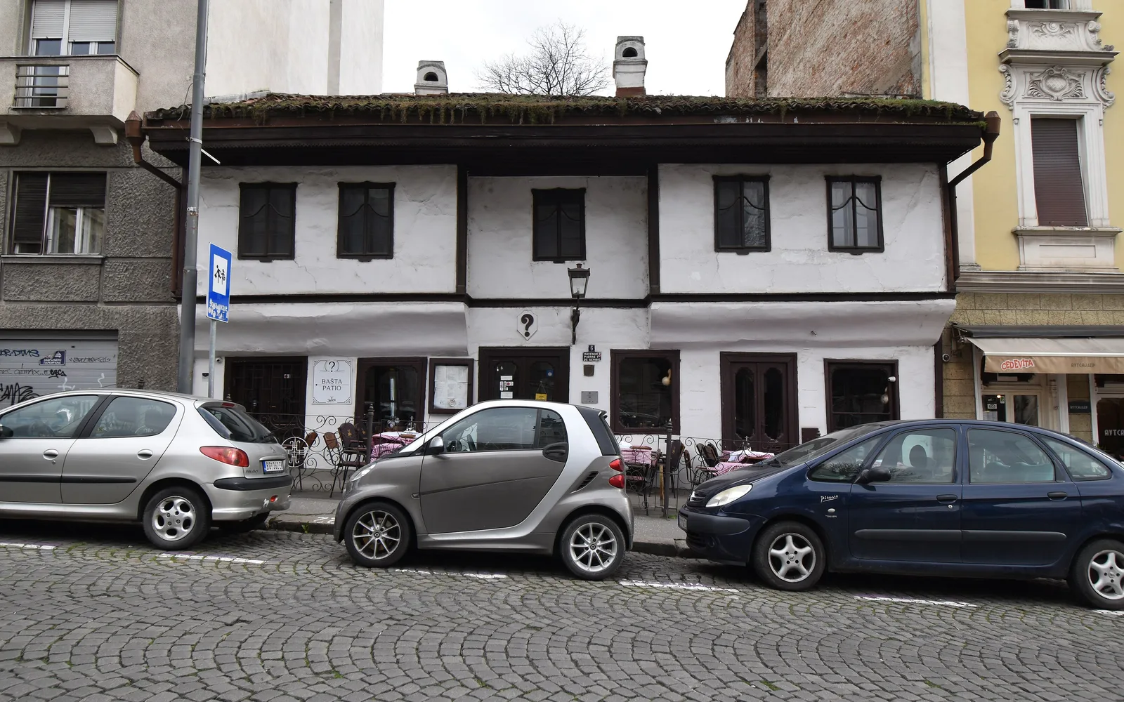 The low white 1823 house of Kafana "?" at Kralja Petra 6, Belgrade, with a small question-mark sign above the door and a cobbled street in front