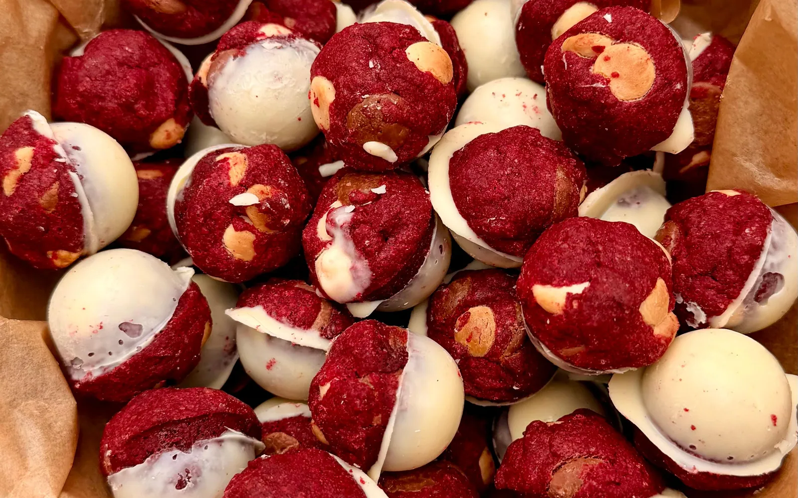 Top-down view of red velvet cookie balls with chocolate chips, each set in a half-sphere shell of white chocolate