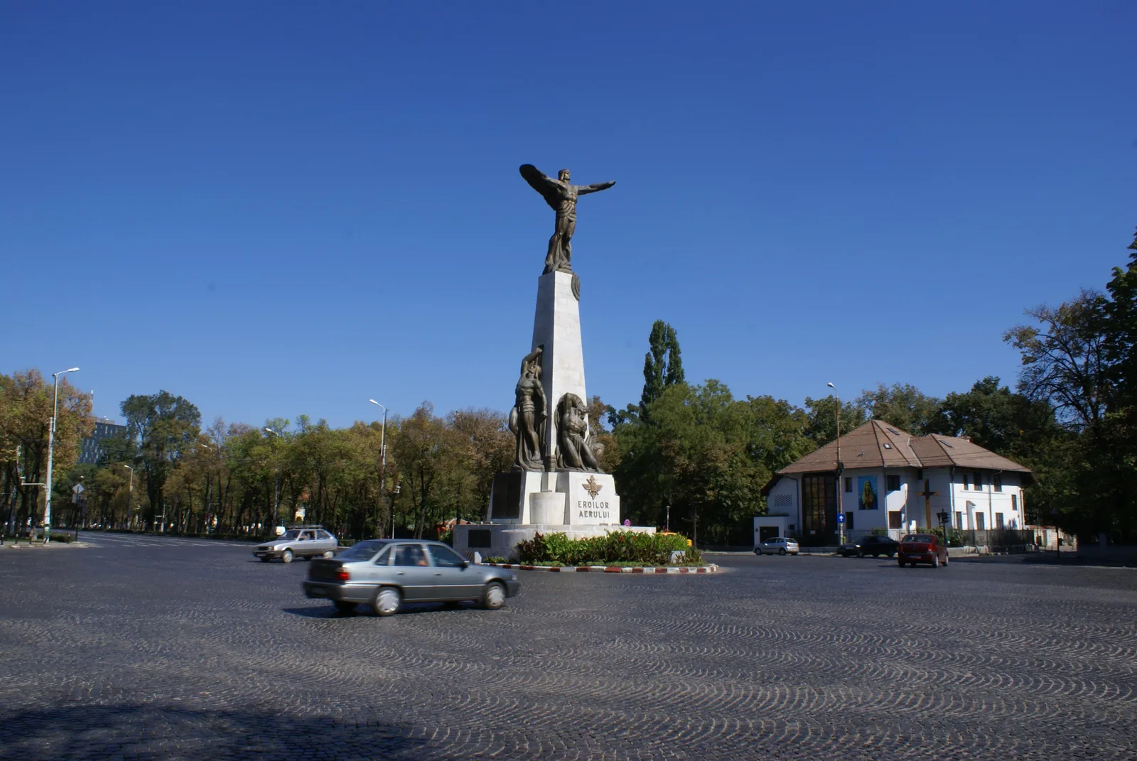 The Monument to the Heroes of the Air in Piața Aviatorilor, Bucharest: a bronze winged figure on top of a tall stone obelisk against a blue sky
