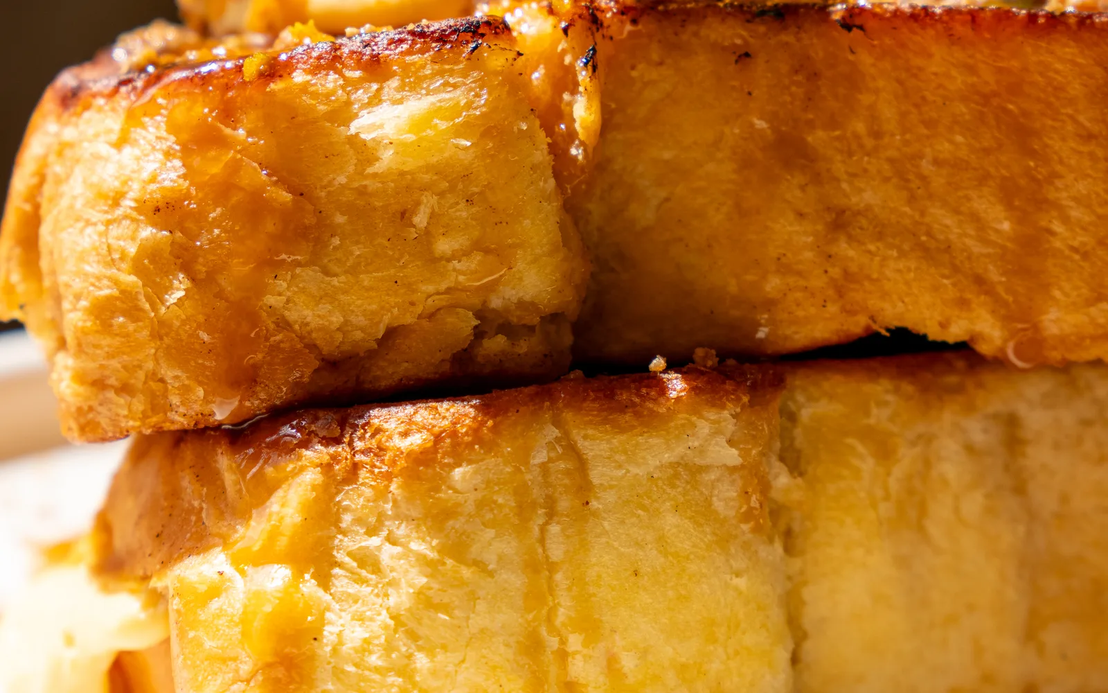 Side view of the Crème Brûlée French Toast at Cookie Beacon Budapest: the soft crumb of two thick brioche slices, one stacked on the other, with a glossy browned crust