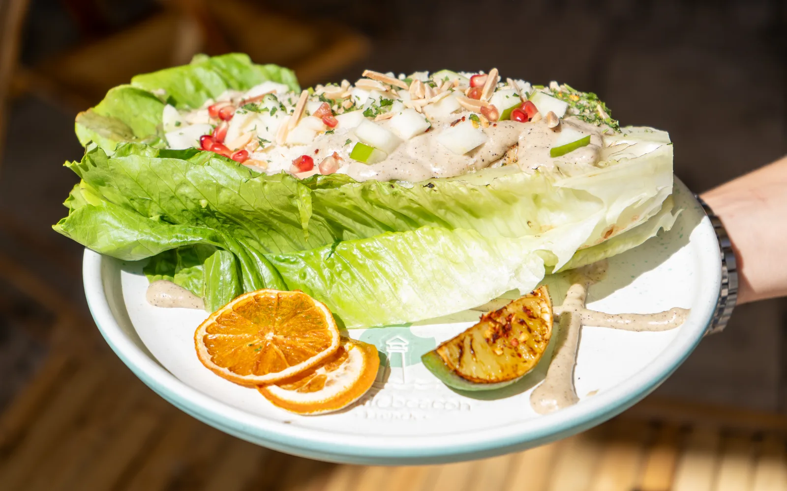 Grilled-Romaine Caesar Crunch at Cookie Beacon Budapest: a whole grilled romaine head under keto Caesar sauce, diced apple, pomegranate and toasted almond, with a charred lime and dried orange on the plate