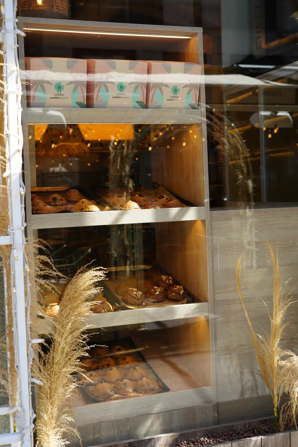 Trays of chunky cookies on lit wooden shelves behind the window at Cookie Beacon Kralja Petra in Belgrade's old town