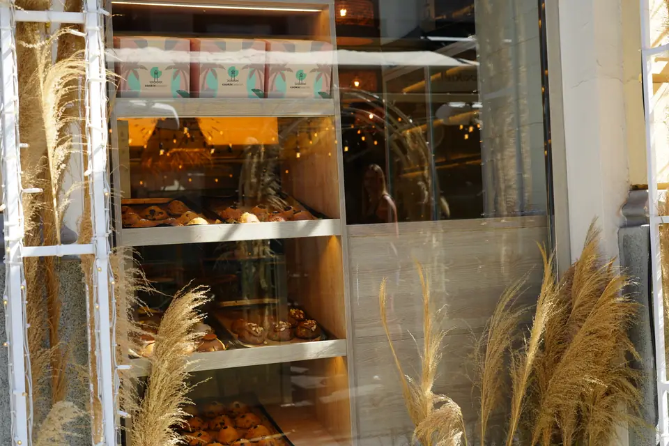 The lit shelves of cookies and pastries at Cookie Beacon Kralja Petra seen through the window from the street in Belgrade's old town