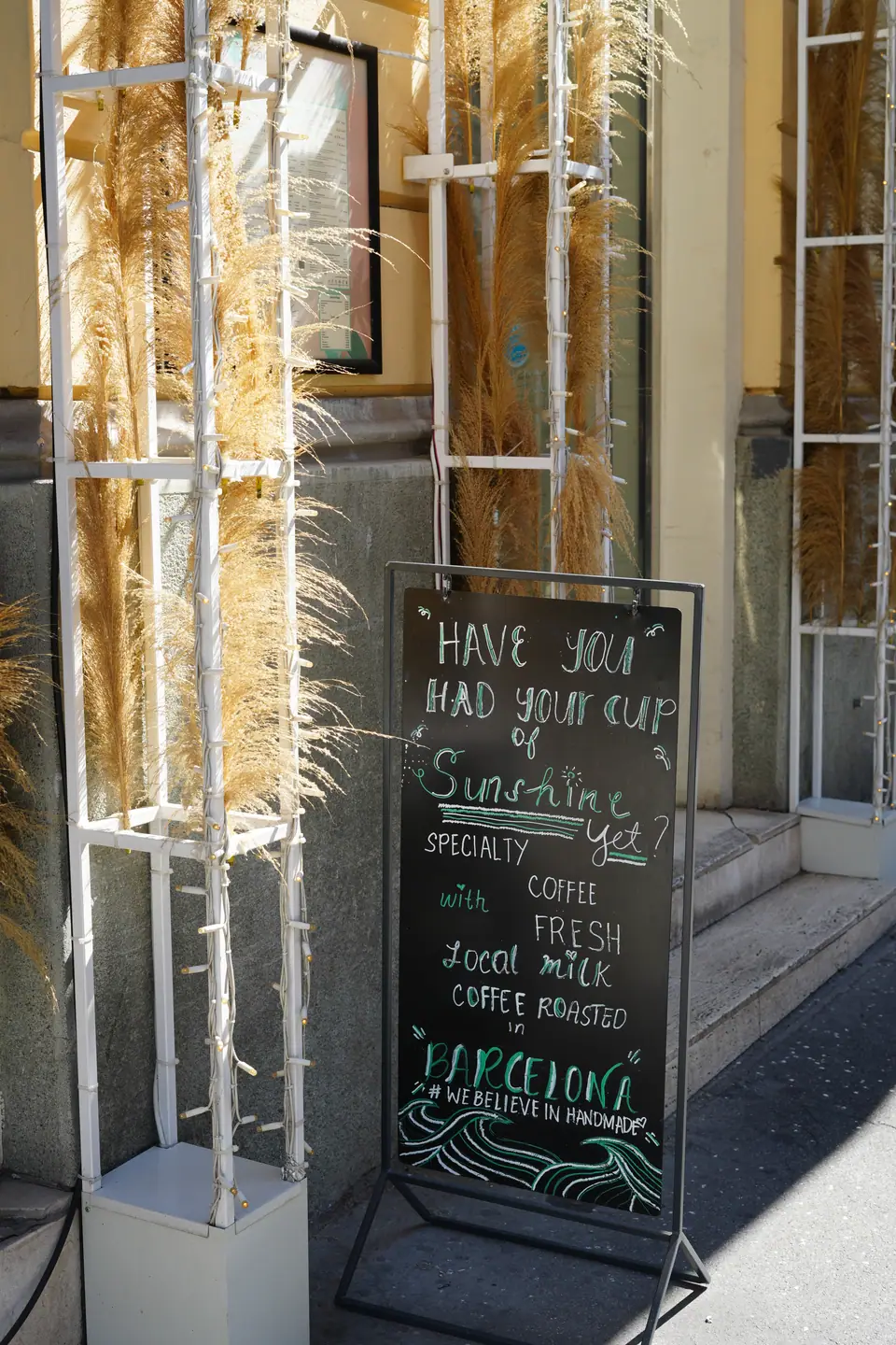A pavement chalkboard outside Cookie Beacon Kralja Petra in Belgrade reading Have you had your cup of sunshine yet, specialty coffee with fresh local milk, coffee roasted in Barcelona