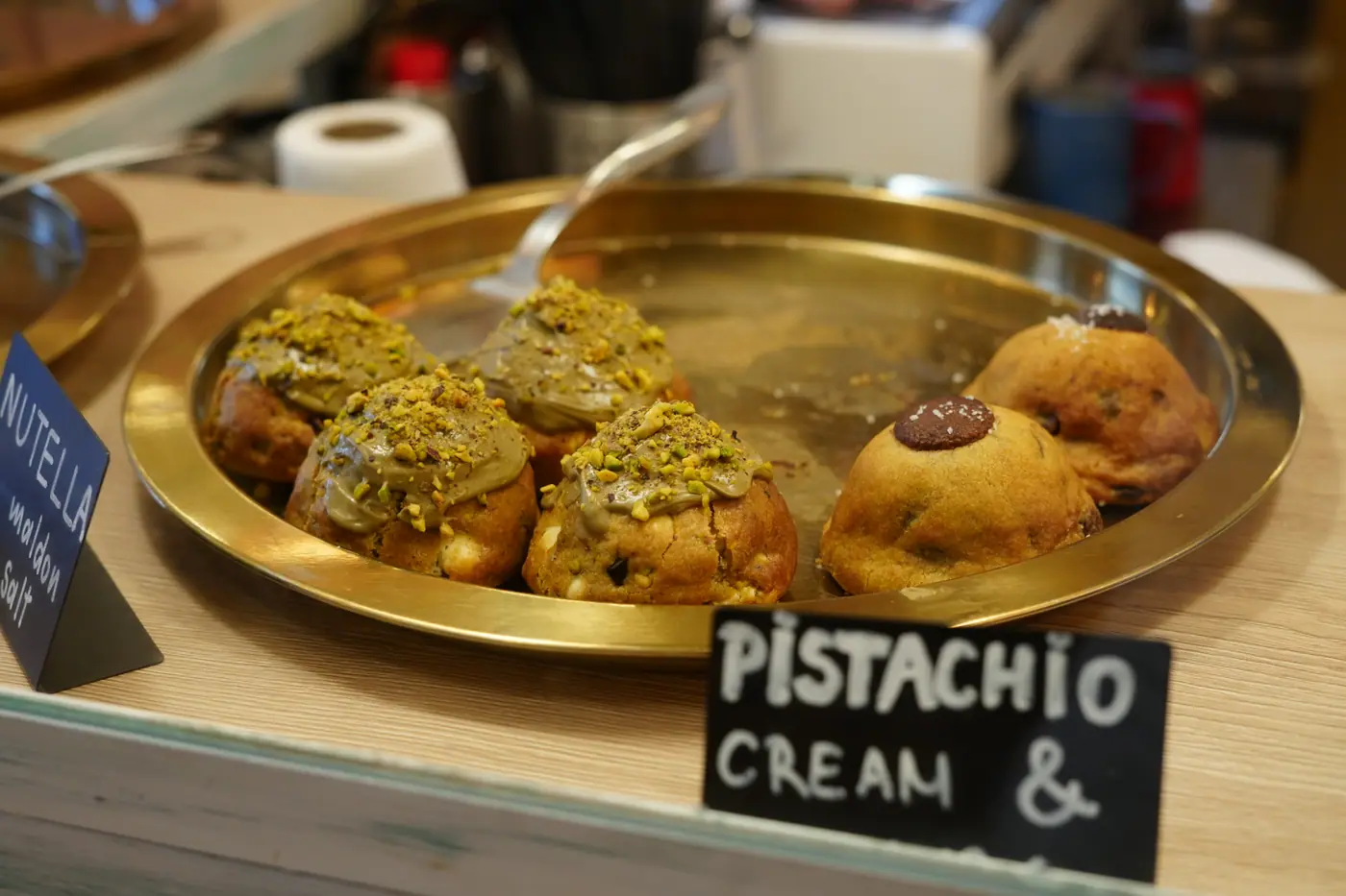 Chunky cookies topped with pistachio cream on a brass tray at Cookie Beacon Kralja Petra in Belgrade