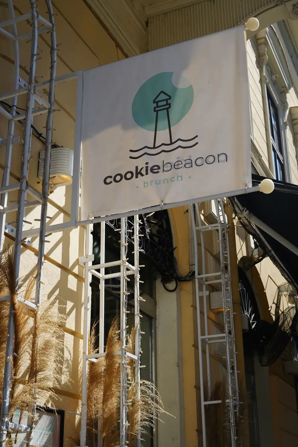 The round cookiebeacon brunch sign hanging from the facade above the entrance to Cookie Beacon Kralja Petra in Belgrade's old town