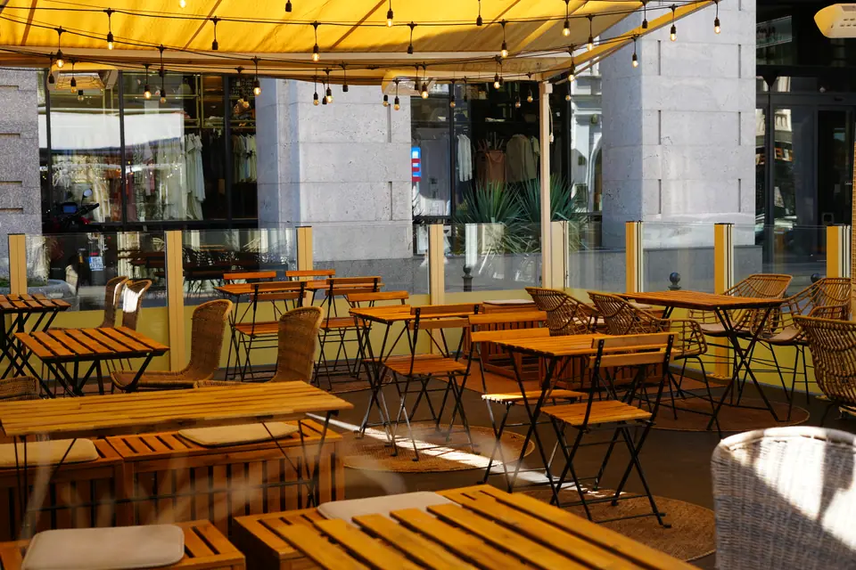 Folding slatted tables and rattan chairs on the pavement terrace of Cookie Beacon Kralja Petra in Stari Grad, Belgrade, with the old town street behind