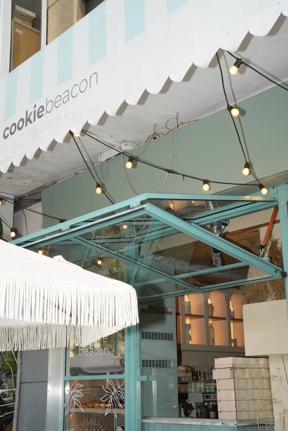 The white scalloped awning lettered cookiebeacon brunch above the mint-green glass frontage of Cookie Beacon Amzei on Strada General Christian Tell in central Bucharest