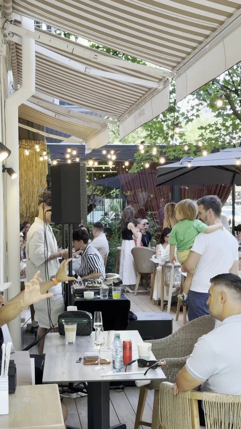 Guests at tables under parasols and festoon lights on the garden terrace at Cookie Beacon Floreasca, Bucharest, in a still from the cafe's own short film