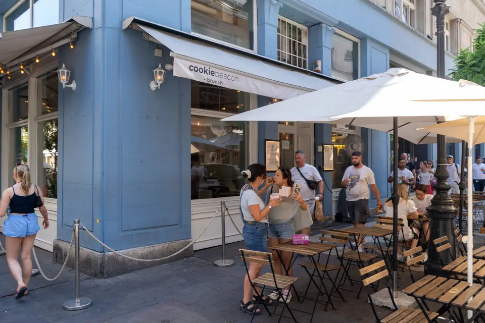 The blue corner façade of Cookie Beacon on Hercegprímás utca in Budapest, with pavement tables under a white parasol