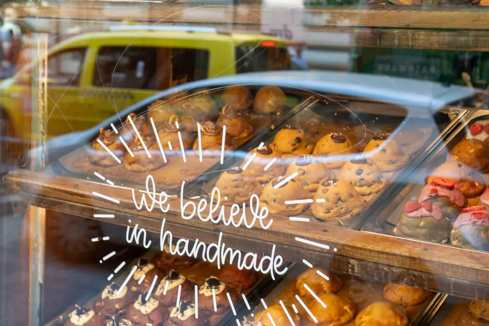 Trays of chunky cookies in the window display of Cookie Beacon Budapest, with the street reflected in the glass
