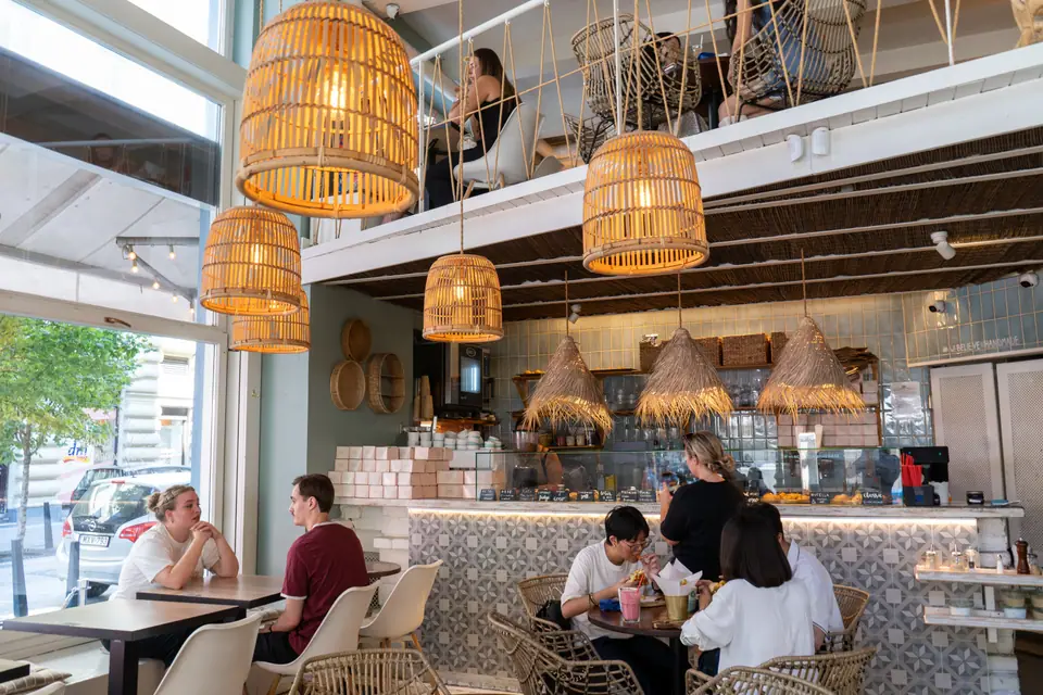 The double-height ground floor of Cookie Beacon Budapest with the white mezzanine above and guests at tables below