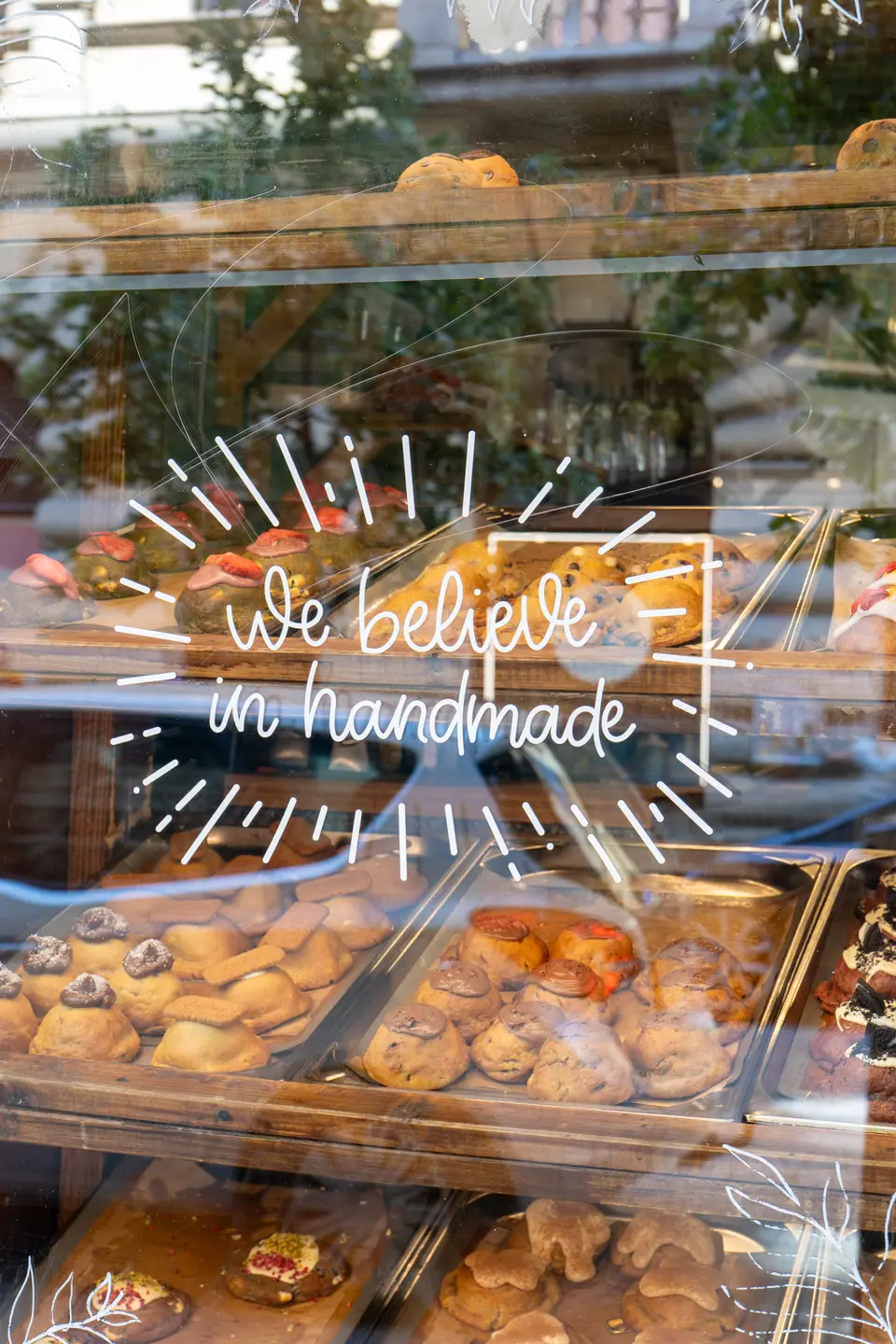 Close-up of the hand-lettered "We believe in handmade" sign on the Cookie Beacon window above the pastry case