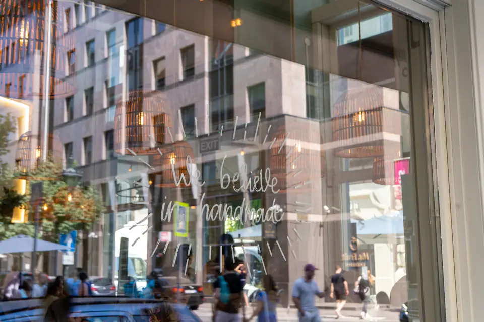 Lipótváros townhouses reflected in the window of Cookie Beacon Budapest over the hand-lettered sign