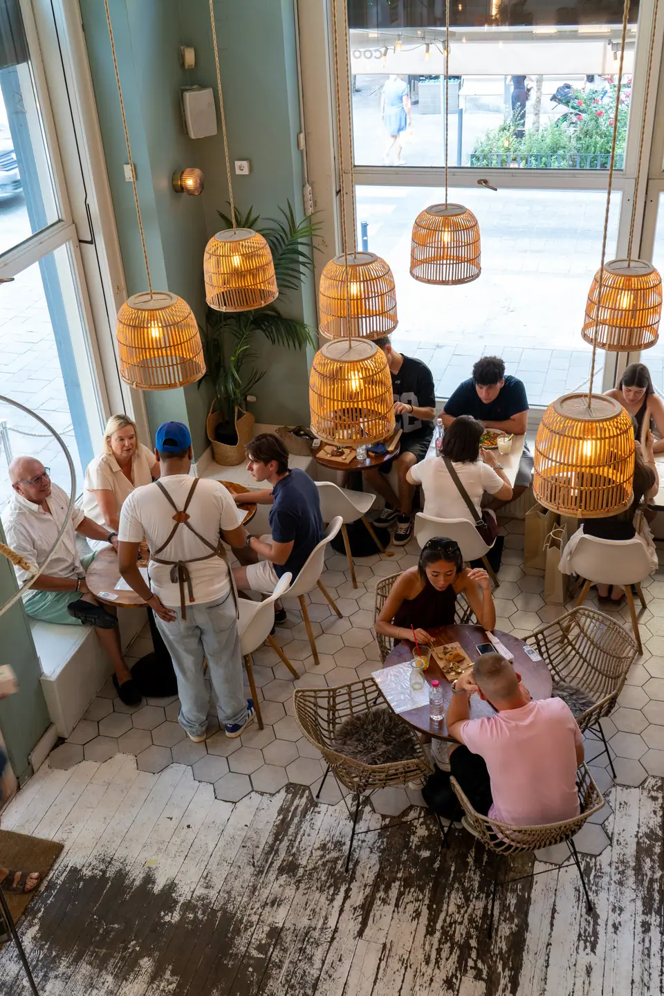 Rattan lamps glowing over guests at brunch on the hexagon-tiled floor of Cookie Beacon Budapest