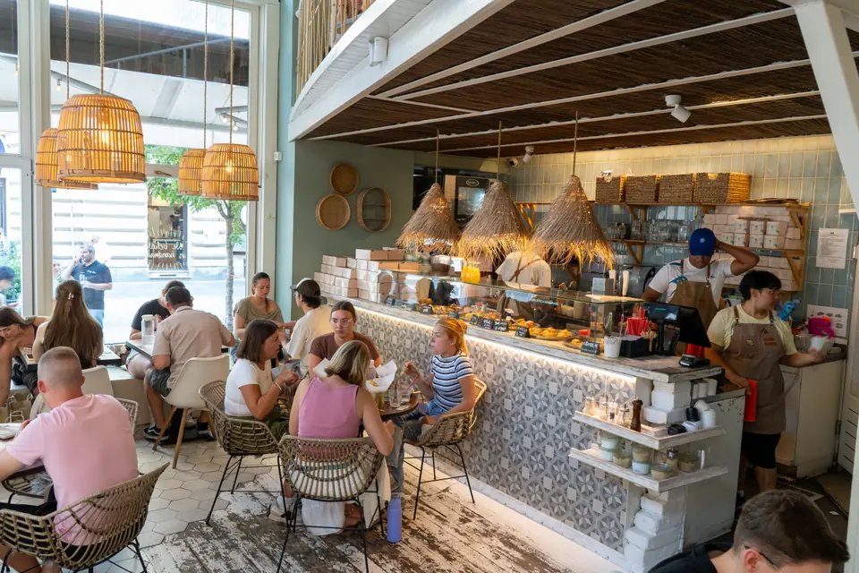 The tiled service counter at Cookie Beacon Budapest with staff working and guests at tables under rattan pendant lamps