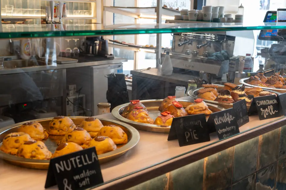 The counter at Cookie Beacon Ferenciek tere with trays of cookies and chalk labels reading Nutella, lemon pie and cinnamon roll