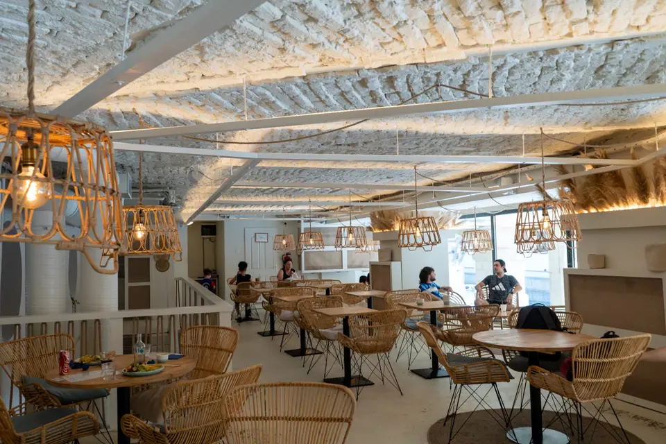Tables and rattan chairs under the vaulted ceiling on the upstairs floor of Cookie Beacon Ferenciek tere