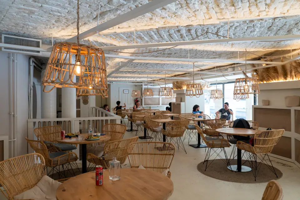 The upstairs room at Cookie Beacon Ferenciek tere with a vaulted whitewashed brick ceiling and woven rattan pendant lamps