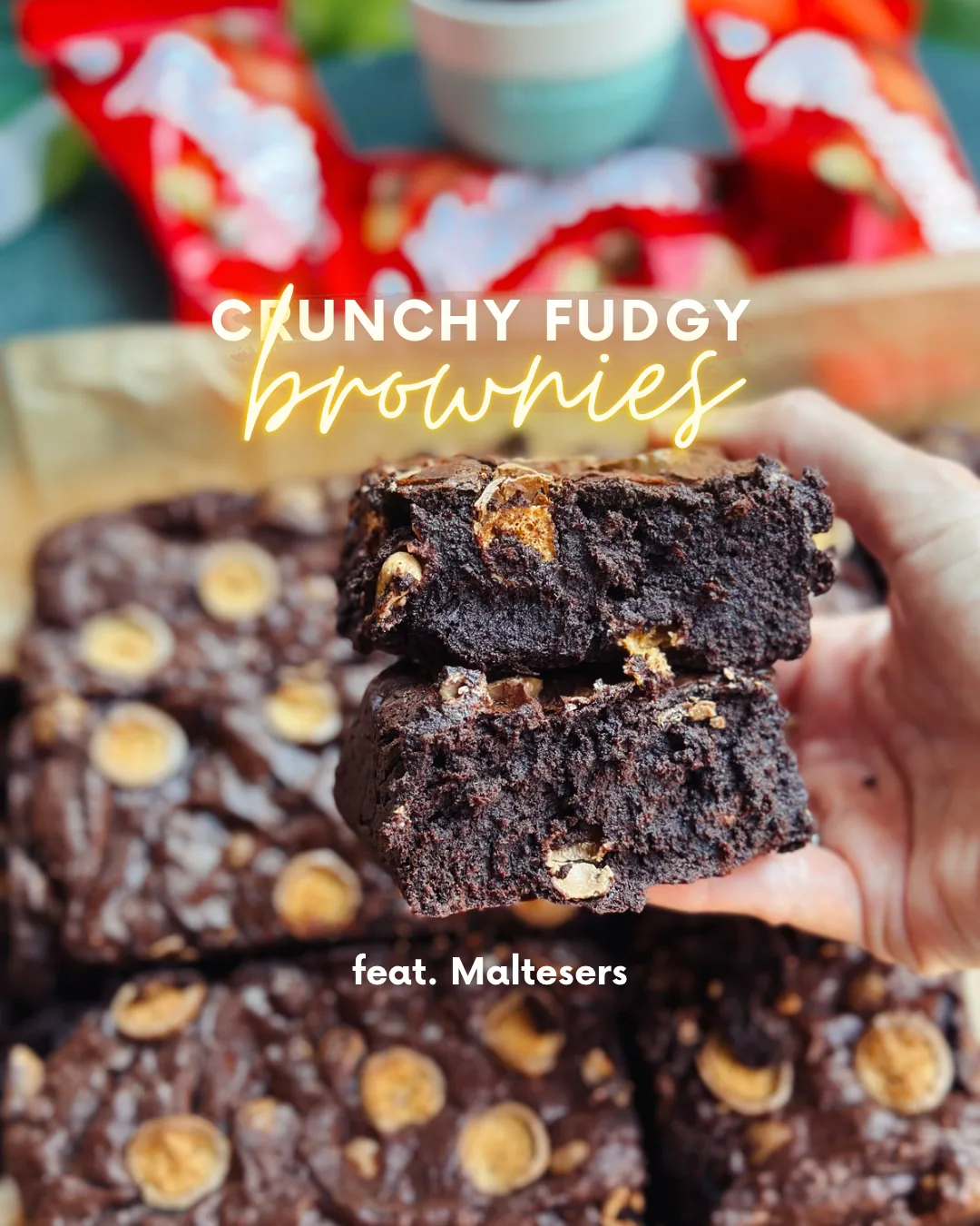 Squares of dark fudgy brownie with a shiny crinkly top and Maltesers baked through