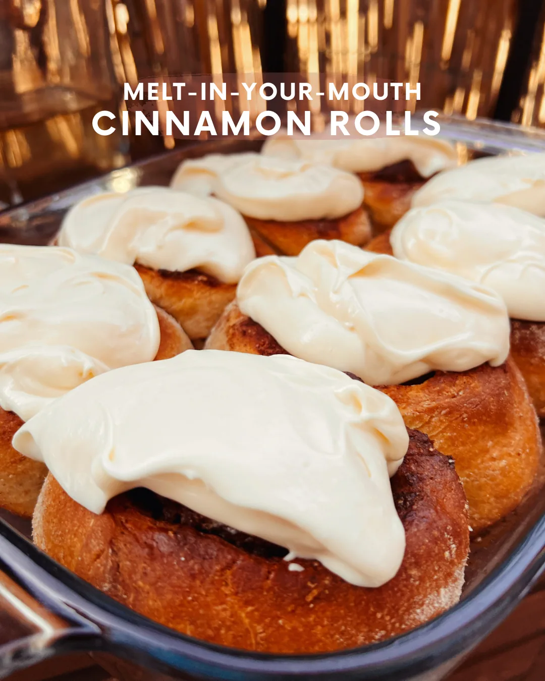 Swirled cinnamon rolls in a baking dish, covered in thick white cream cheese frosting