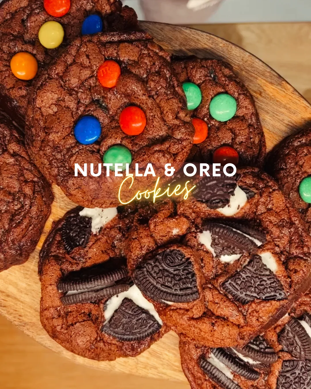 Crackle-topped Nutella cookies on a wooden board, some studded with M&M's, others with Oreo pieces